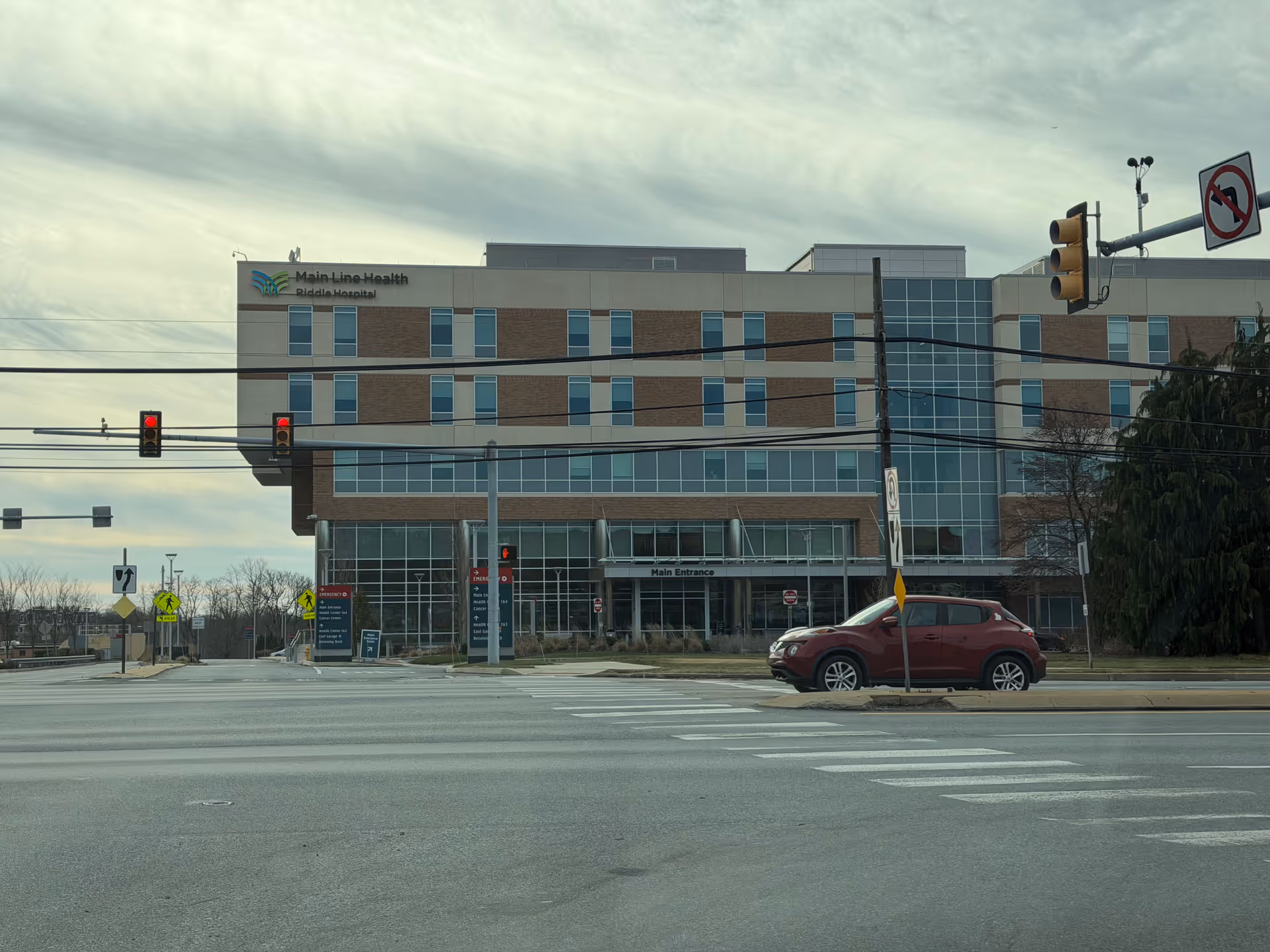 Modern hospital building with glass facade along a busy street.