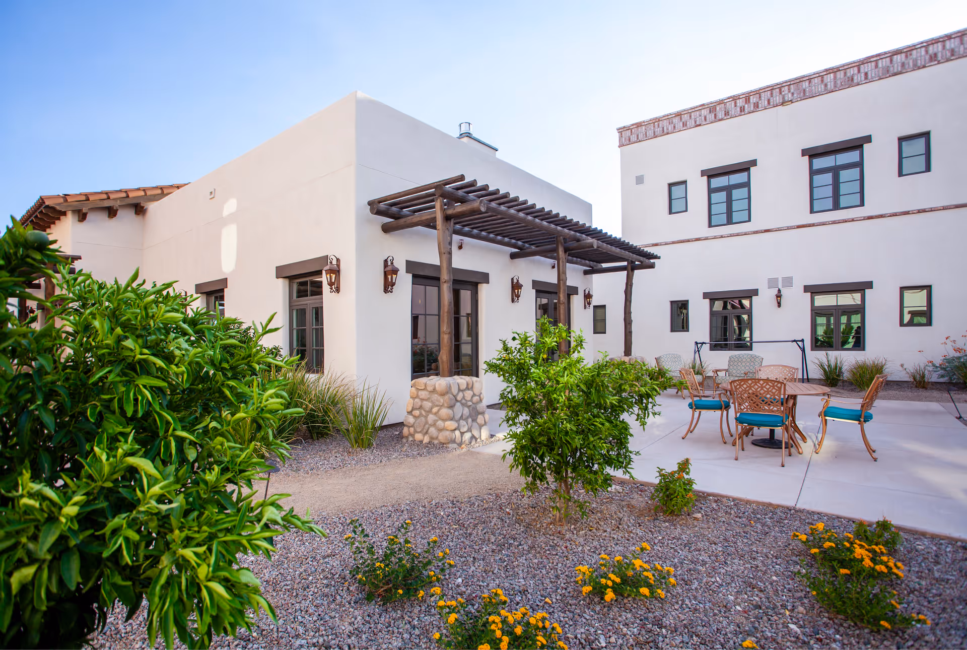 An outdoor courtyard with patio furniture, a pergola, and desert landscaping.