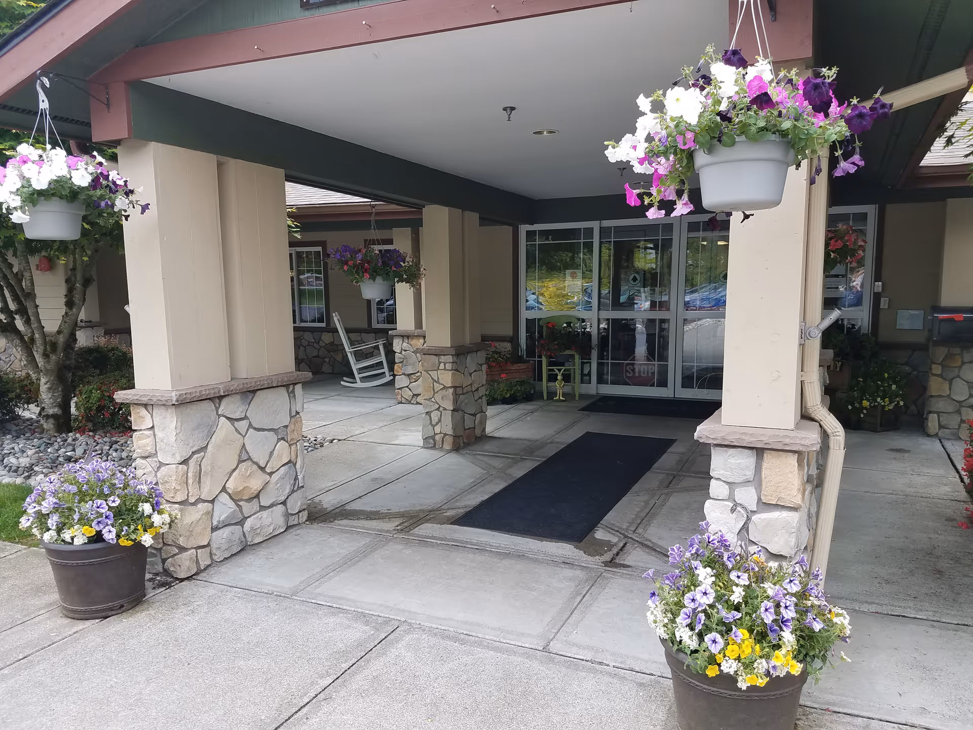 Entrance to Brookdale Arbor Place with hanging baskets and stone columns.