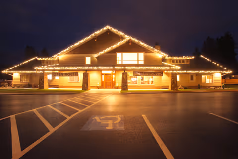 Night exterior of The Lodge at Riverside Harbor, a senior living facility, with string lights.