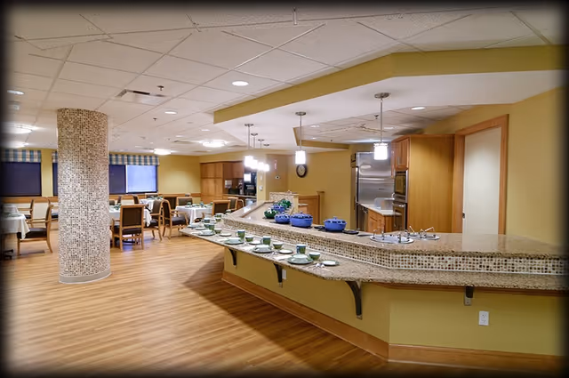 Spacious dining room with a curved mosaic-tiled buffet counter set with dishes, tables and chairs, and wood flooring.