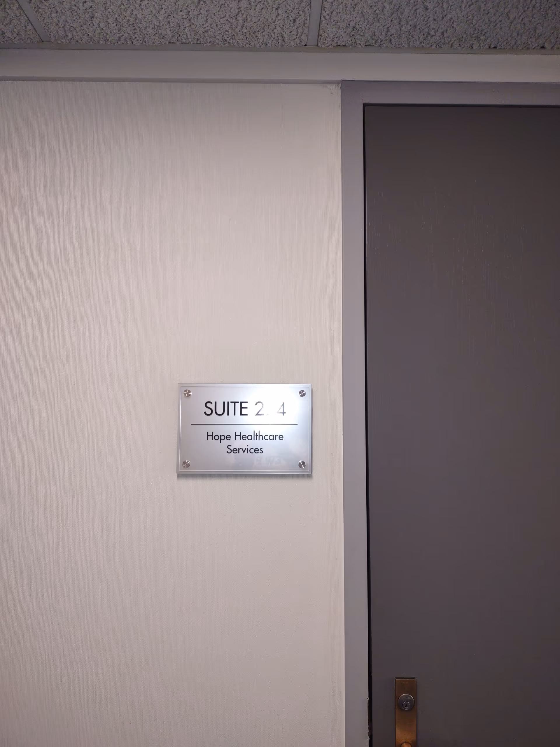 Interior hallway with a plaque reading Suite 2 4 for Hope Healthcare Services.