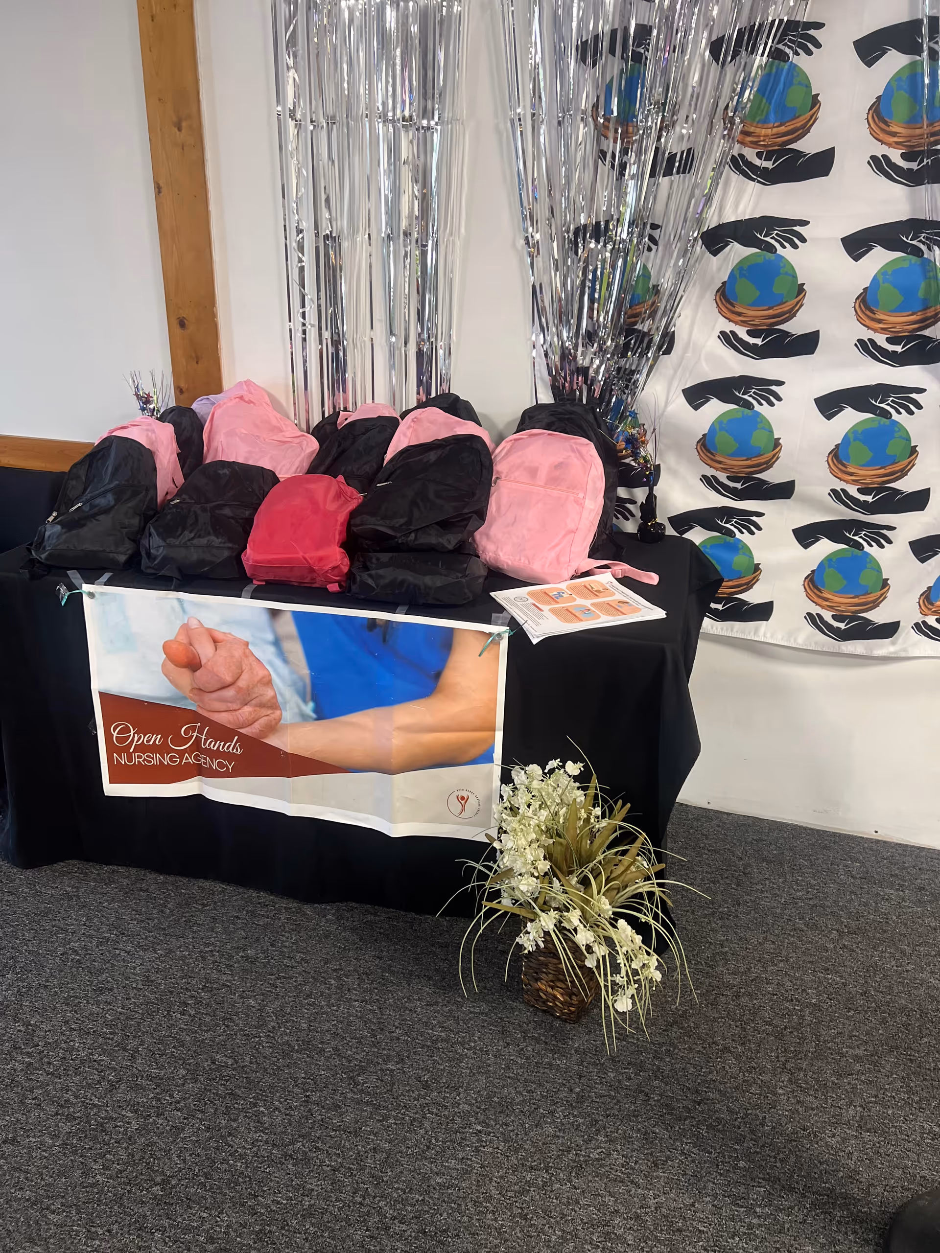 Promotional display for Open Hands Nursing Agency featuring pink and black bags.