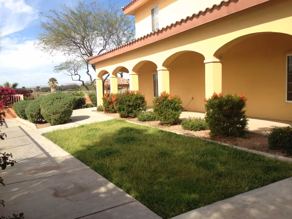 Pennington Gardens exterior: yellow building with arches and manicured landscaping.