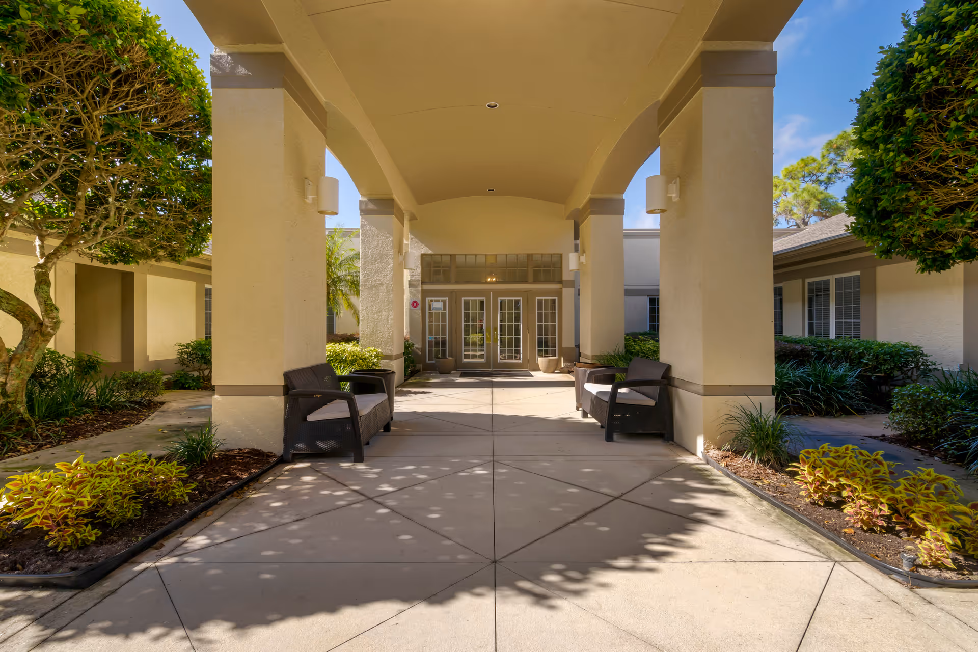 Covered entrance with large columns, benches, and landscaped planters at Brookdale Deer Creek Sarasota.
