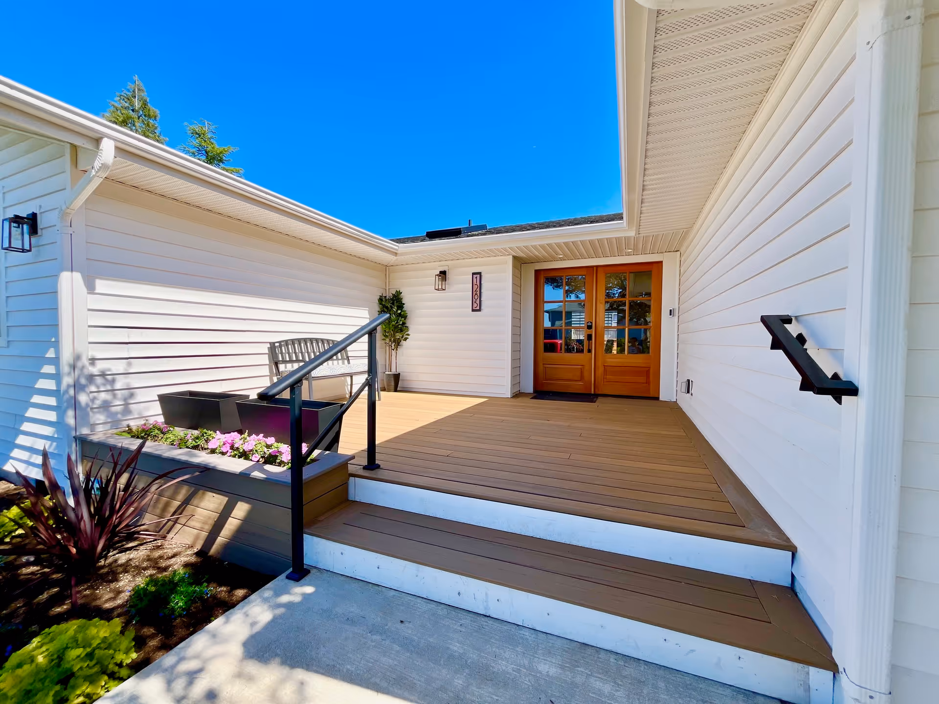 Entrance to a white building with a wooden door and small deck.