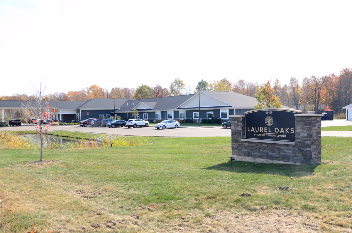 Exterior view of Laurel Oaks Senior Living with sign, building, and parking lot.