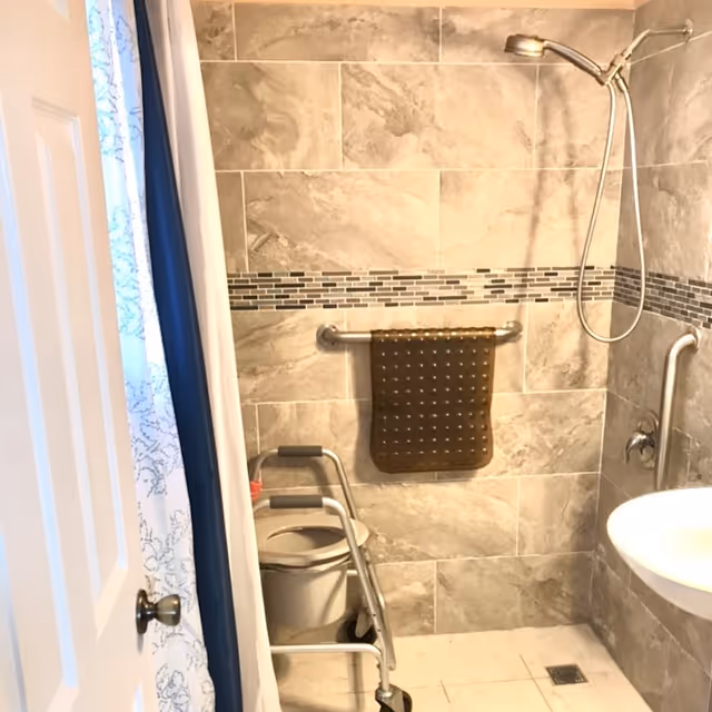 Accessible bathroom with tiled walls, shower, grab bars, and a walker.