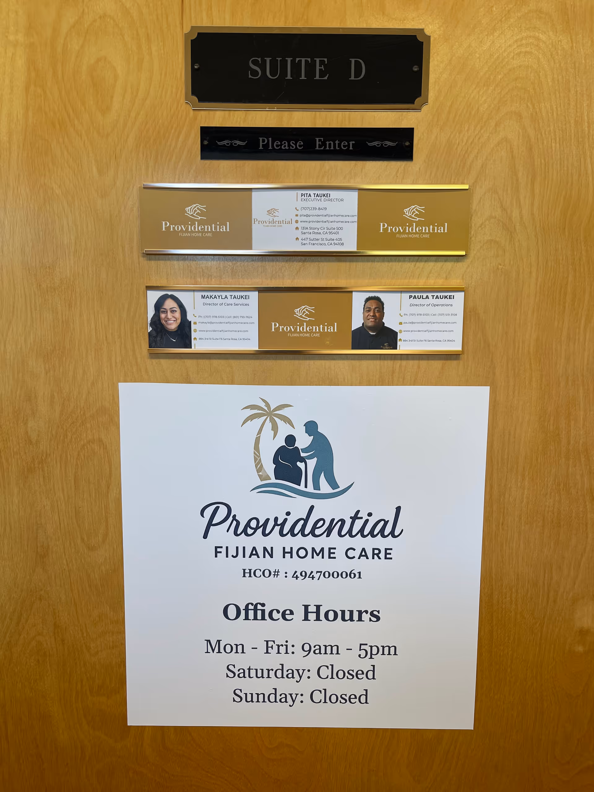 Wooden interior door with Suite D sign, nameplates, and Providential Fijian Home Care office hours.