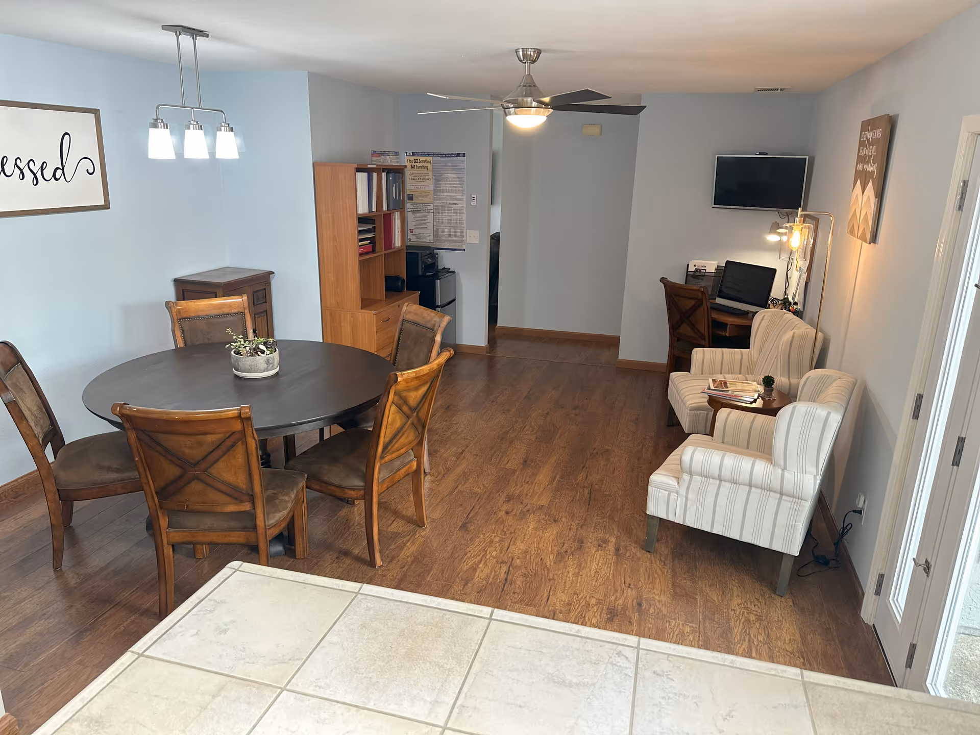 Senior living facility common area with round dining table, chairs, and seating area.