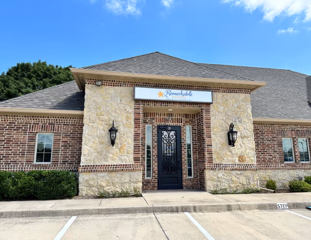 Exterior view of Remarkable Hospice of South Dallas building with brick, stone facade, and entrance door.