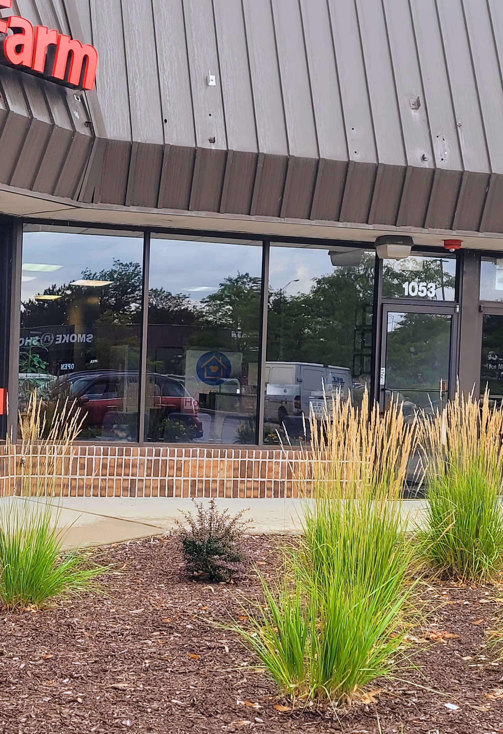 Front exterior of a building with large windows and a landscaped entrance area.