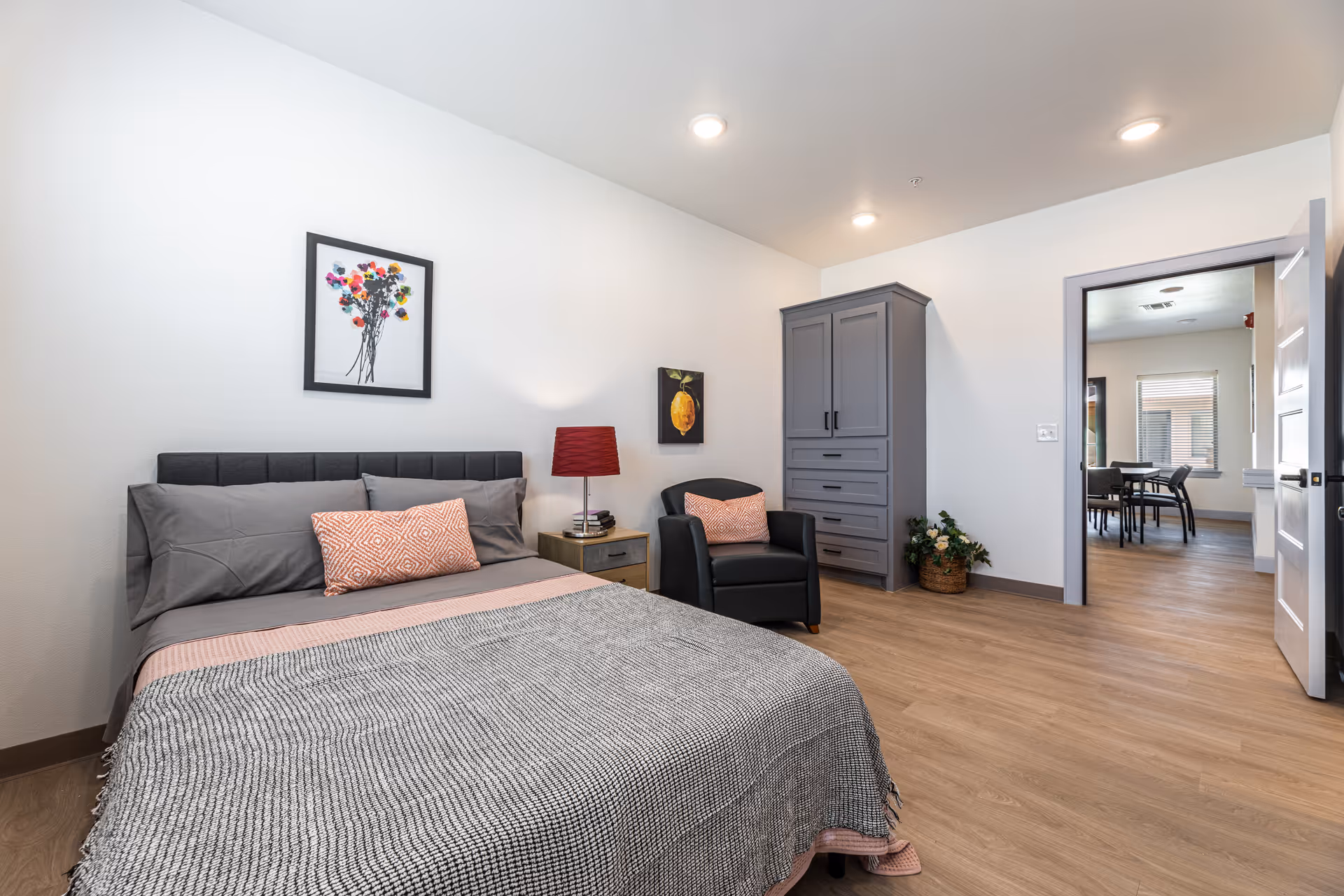 Cozy furnished bedroom at The Lodge Assisted Living with bed, chair, wardrobe, and soft decor.
