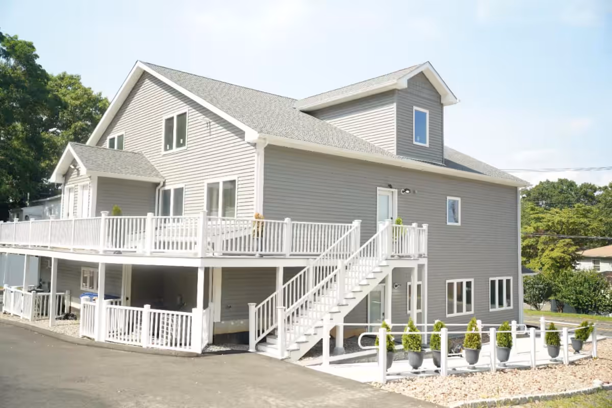 Two-story gray building with white railing and stairs, exterior of a senior facility.