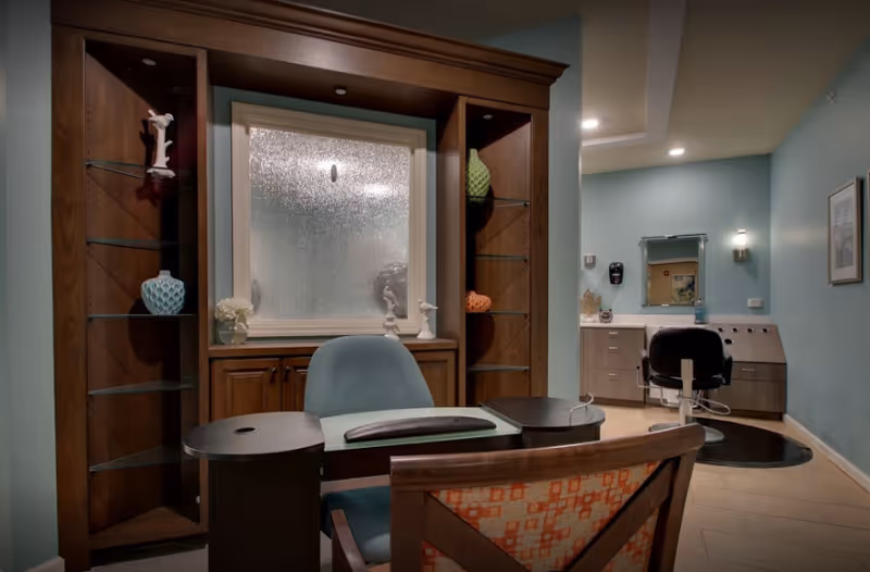 Interior spa/salon area with wooden shelving, frosted window, and teal walls.