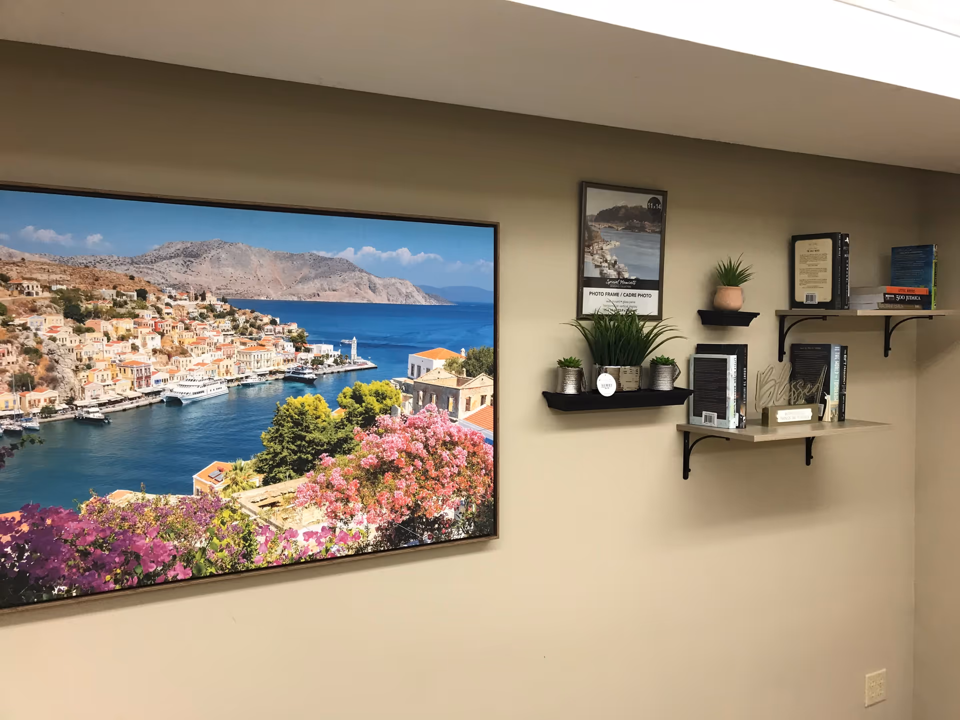 Interior common area with large coastal landscape photo, shelves, and potted plants.