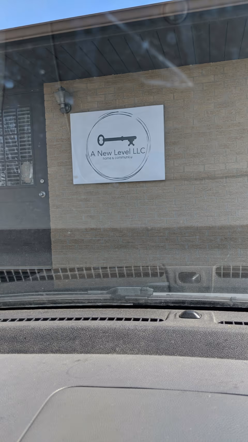 Exterior view of building entrance with a sign for A New Level LLC Home and Community