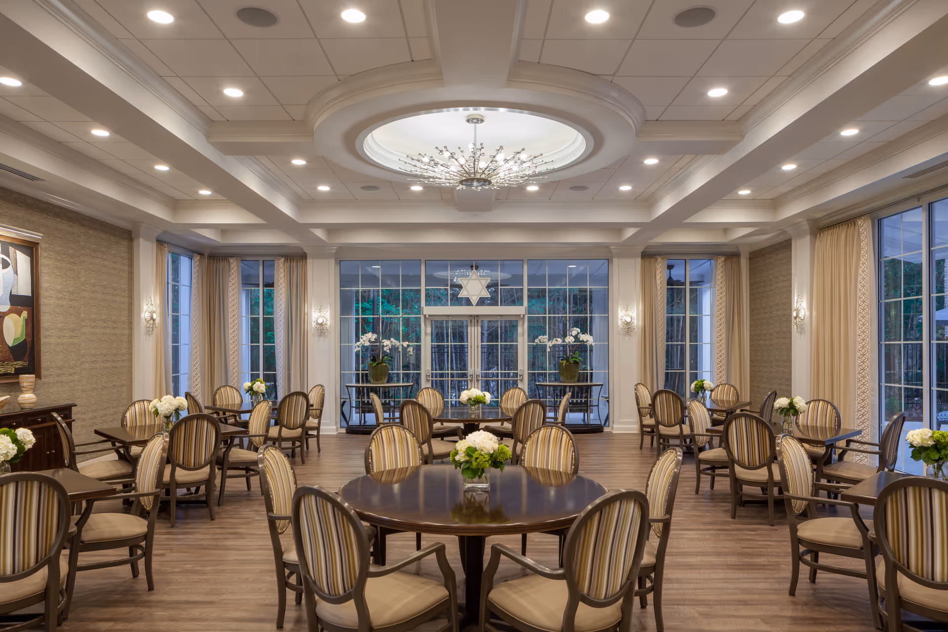 Elegant dining room with round tables, chairs, and floral centerpieces.