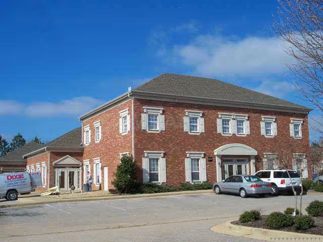 Exterior of HeartBridge Home Care building with brick facade and parked cars.