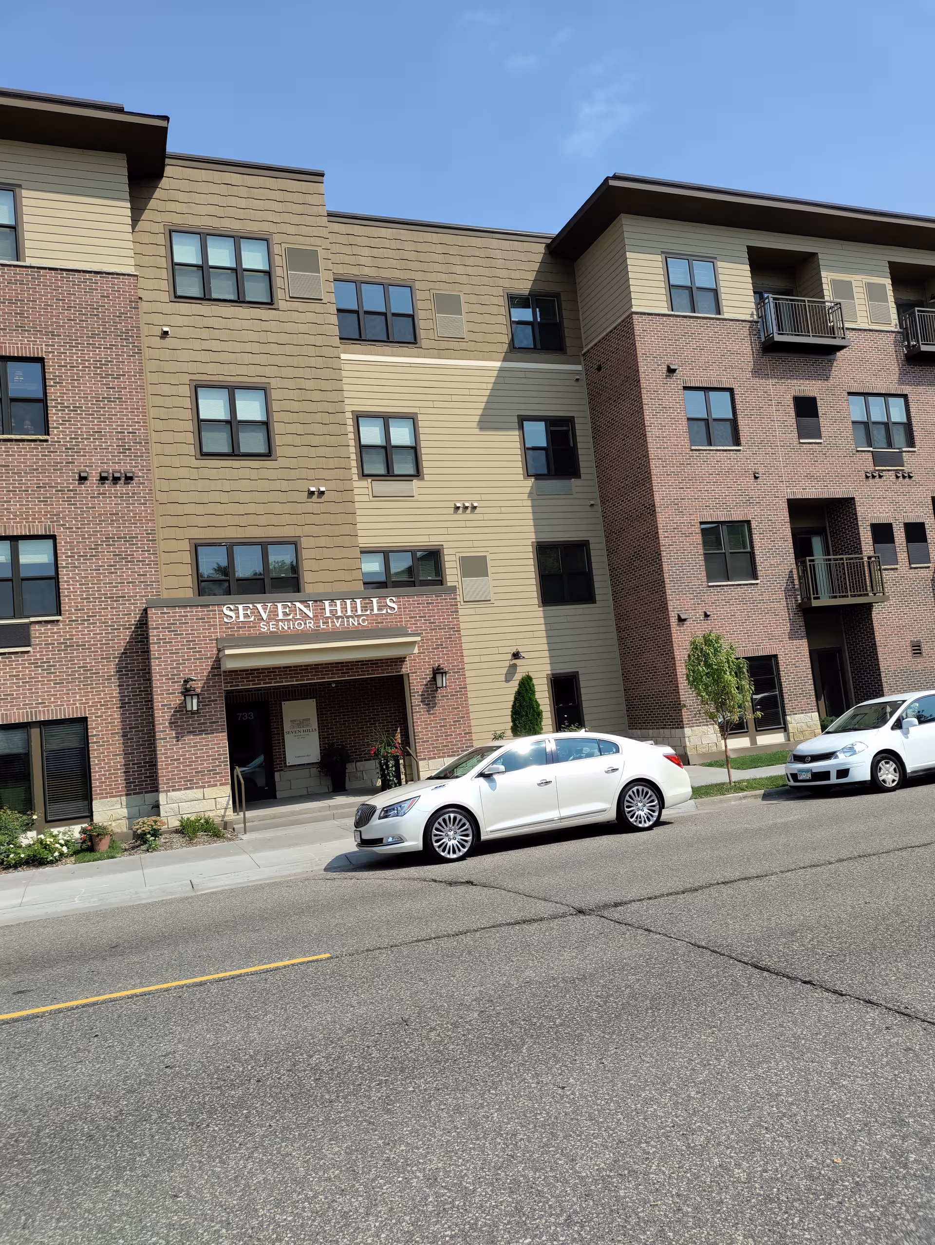 Front view of Seven Hills Senior Living building with parked cars along the street.