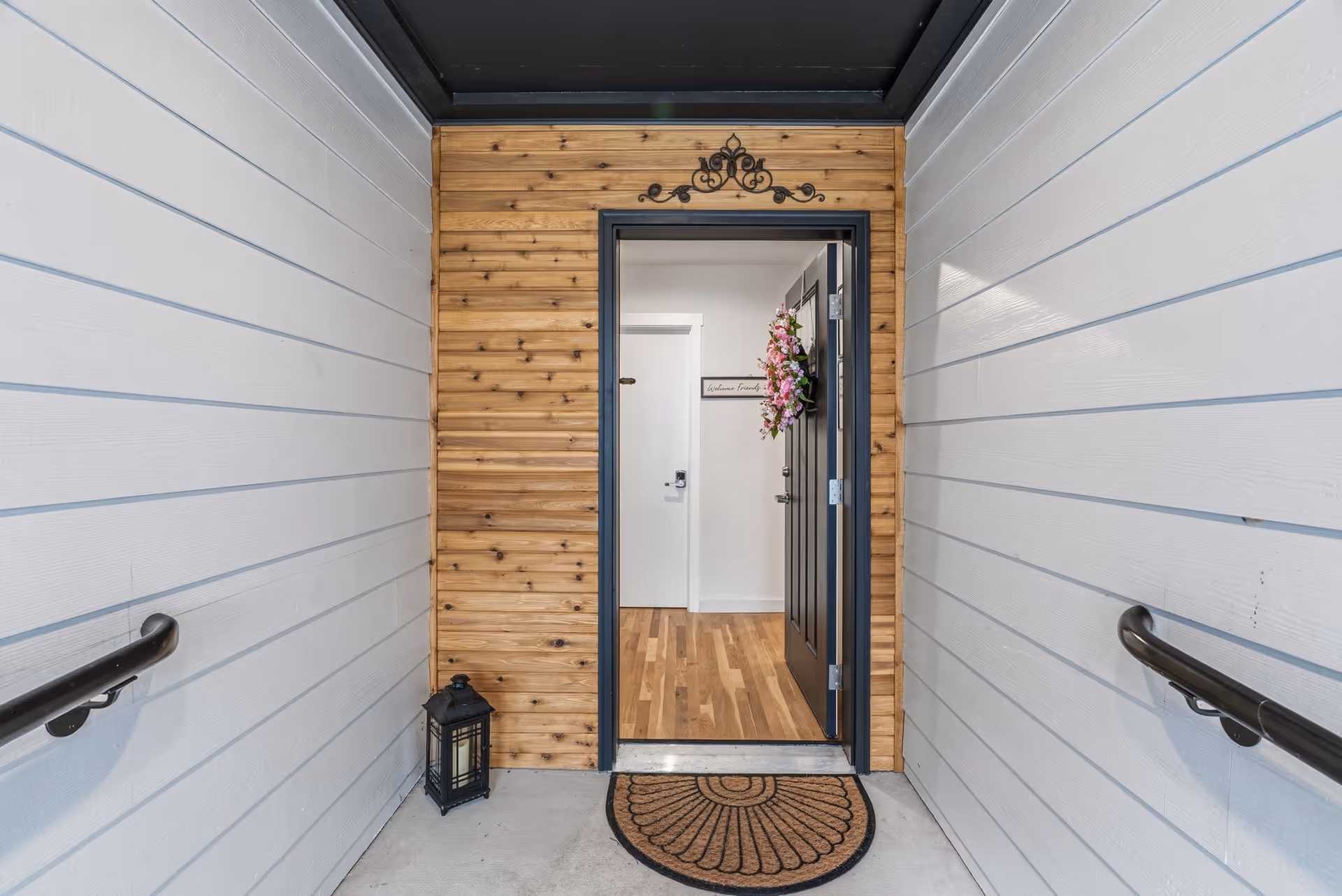 Front entry with wood panel surround, wreath on door, and lantern beside doorstep