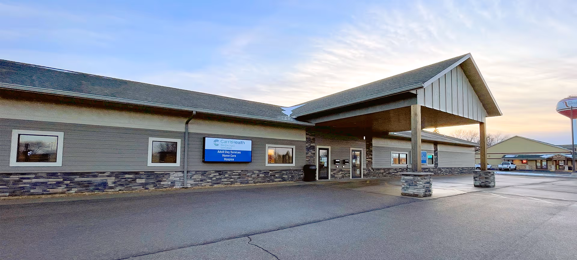 Exterior view of CentraCare Redwood Pavilion with a covered entrance and parking lot