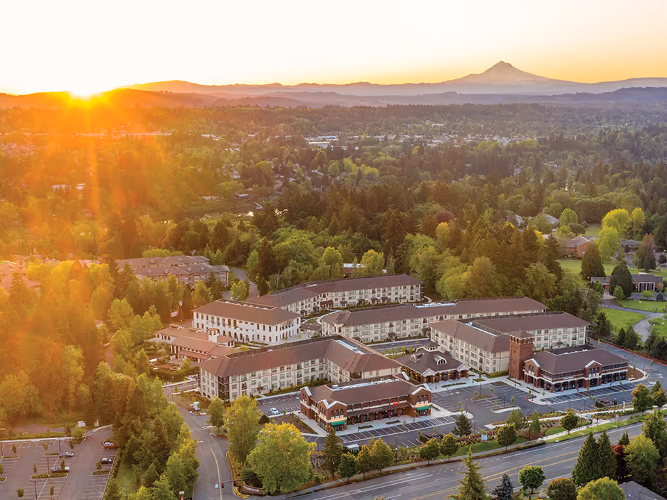 Aerial view of Mary's Woods at Marylhurst campus with several beige buildings, trees, and sunset.