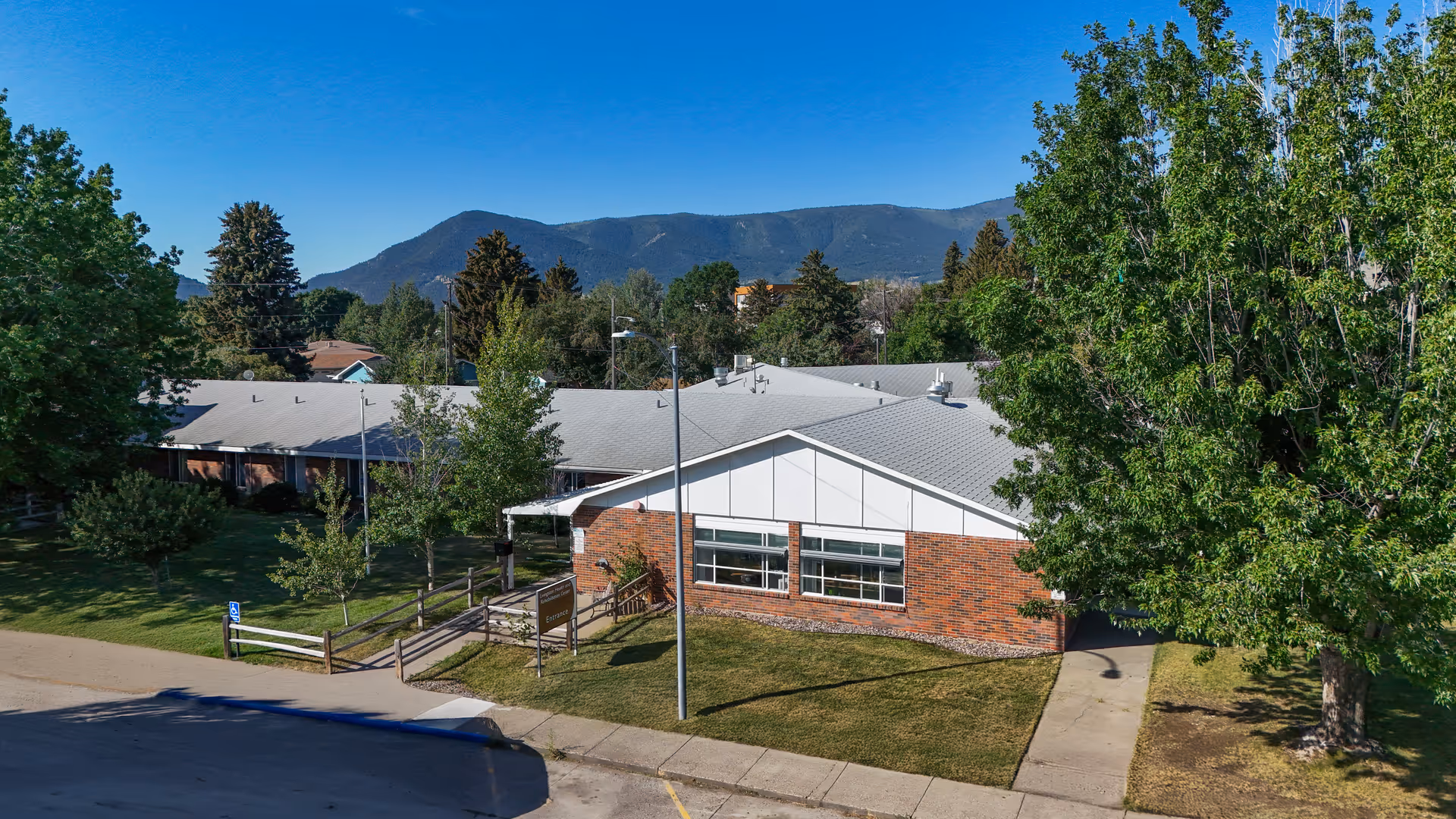 Exterior view of Livingston Health and Rehabilitation Center with brick facade, trees, and mountains.
