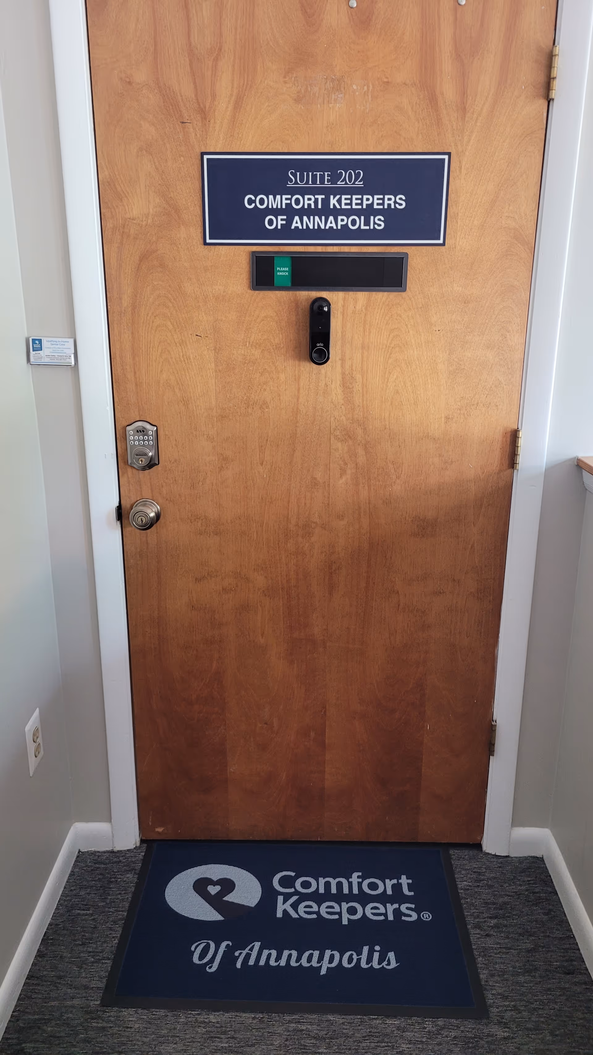 Wooden door labeled Suite 202 with Comfort Keepers mat at entry