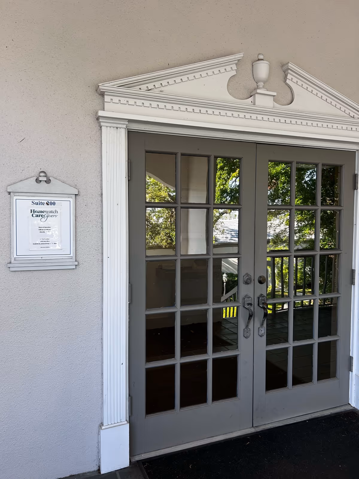Exterior entrance with double glass doors, decorative pediment, and suite plaque.