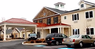 Exterior view of The Birches at Newtown with entrance canopy and parked cars.