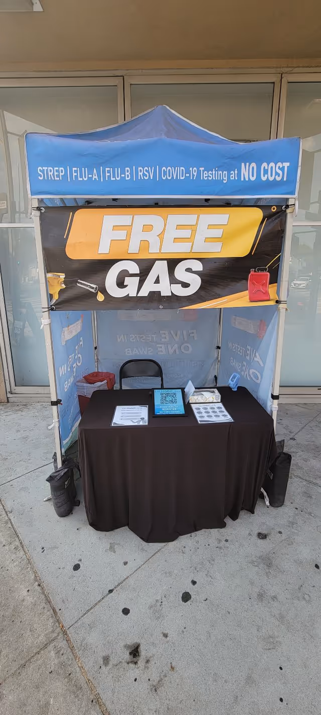 Outdoor tent with banners promoting no-cost testing and free gas.