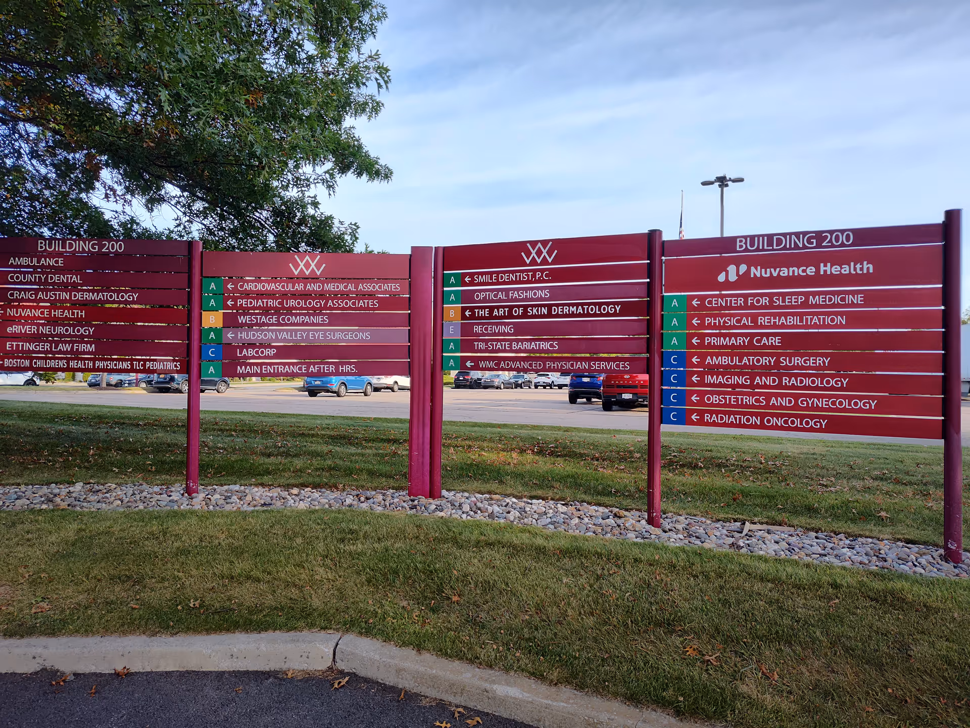 Three maroon outdoor signs listing medical services for Nuvance Health in Fishkill.