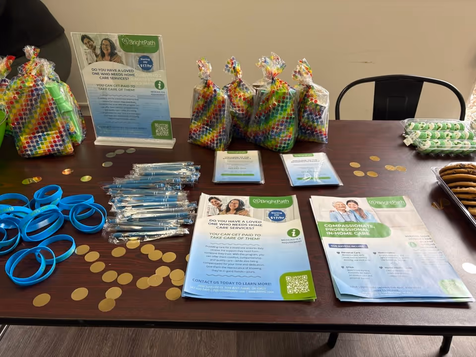 Promotional table showing Bright Path Home Care brochures, gift bags, pens, and wristbands.
