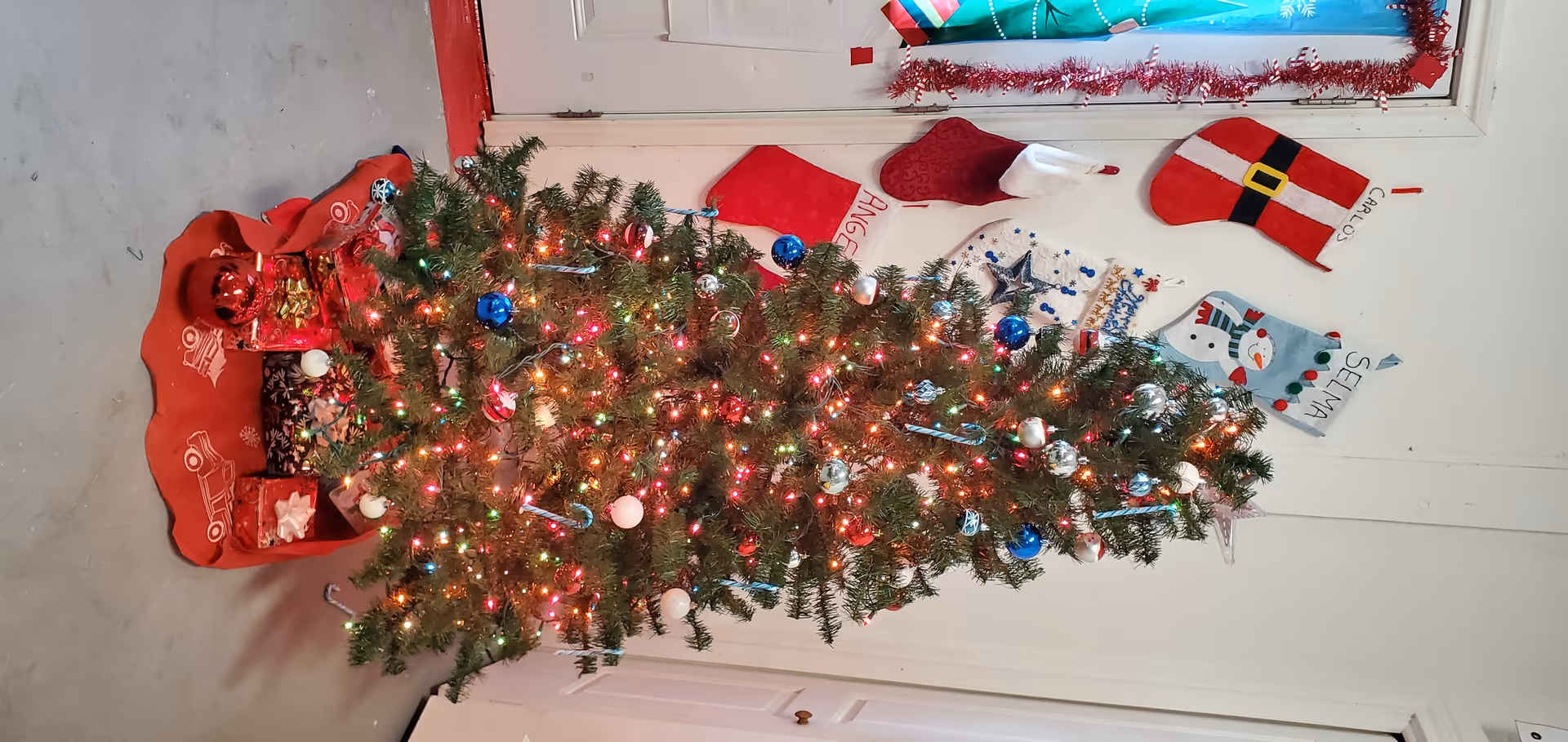 Festively lit Christmas tree stands in an interior facility hallway with holiday decorations.