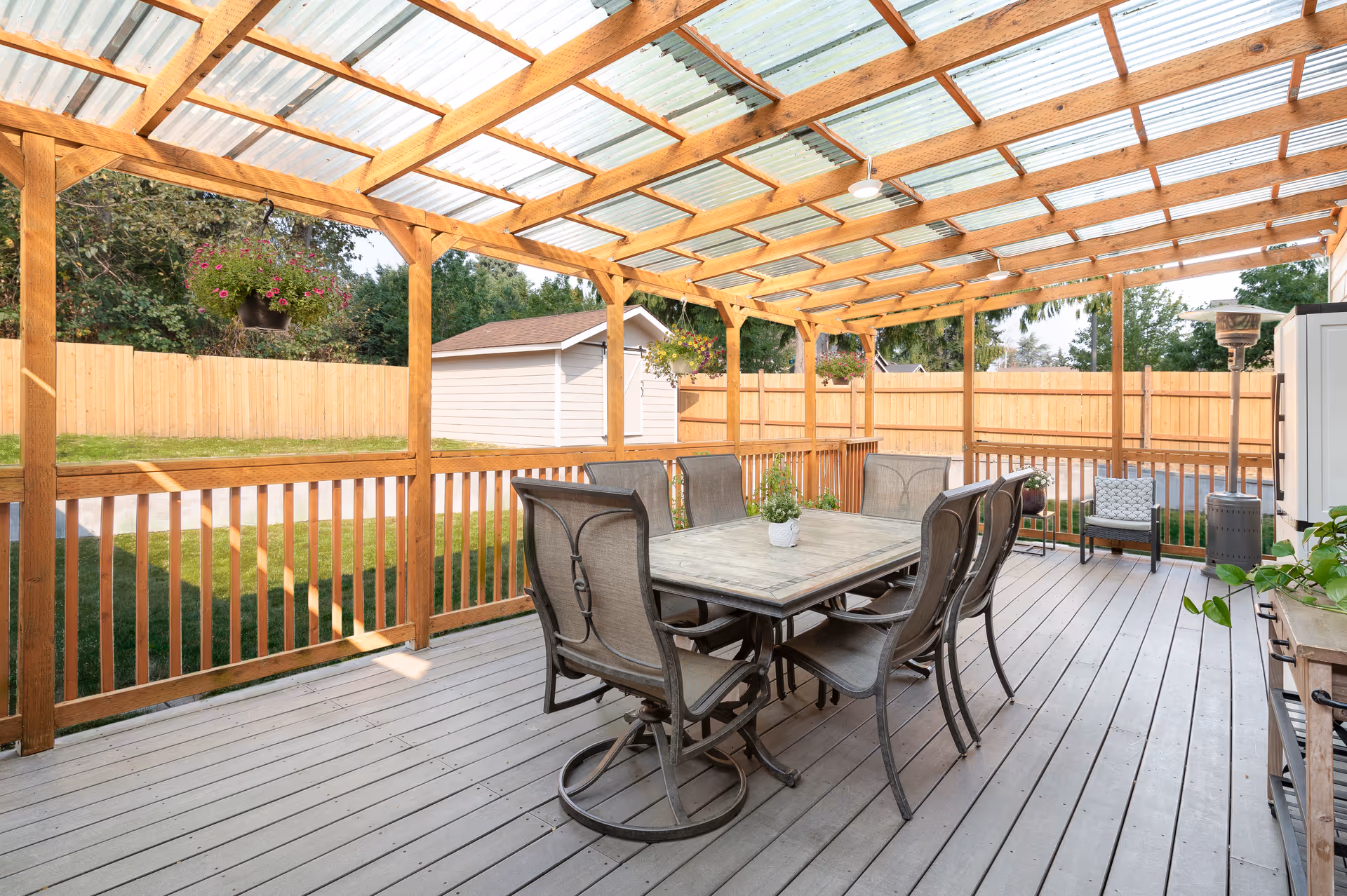 Outdoor wooden deck with a dining table and chairs under a covered pergola.