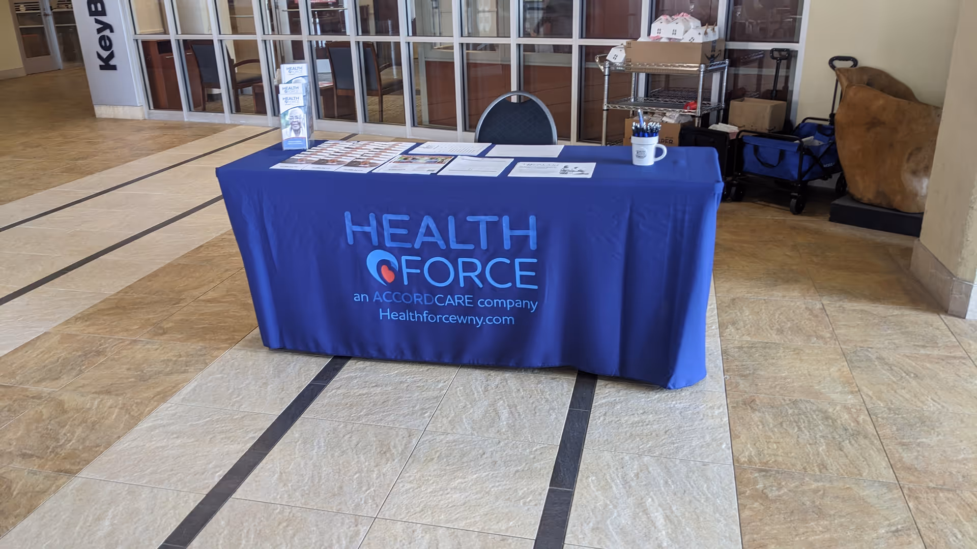 Blue Health Force information table with brochures in a senior living facility lobby.