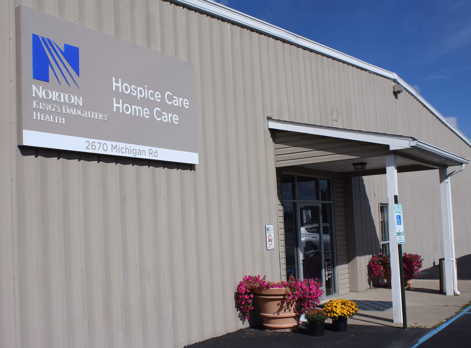 Exterior view of Norton King's Daughters' Health hospice home care building with entrance and colorful planters.