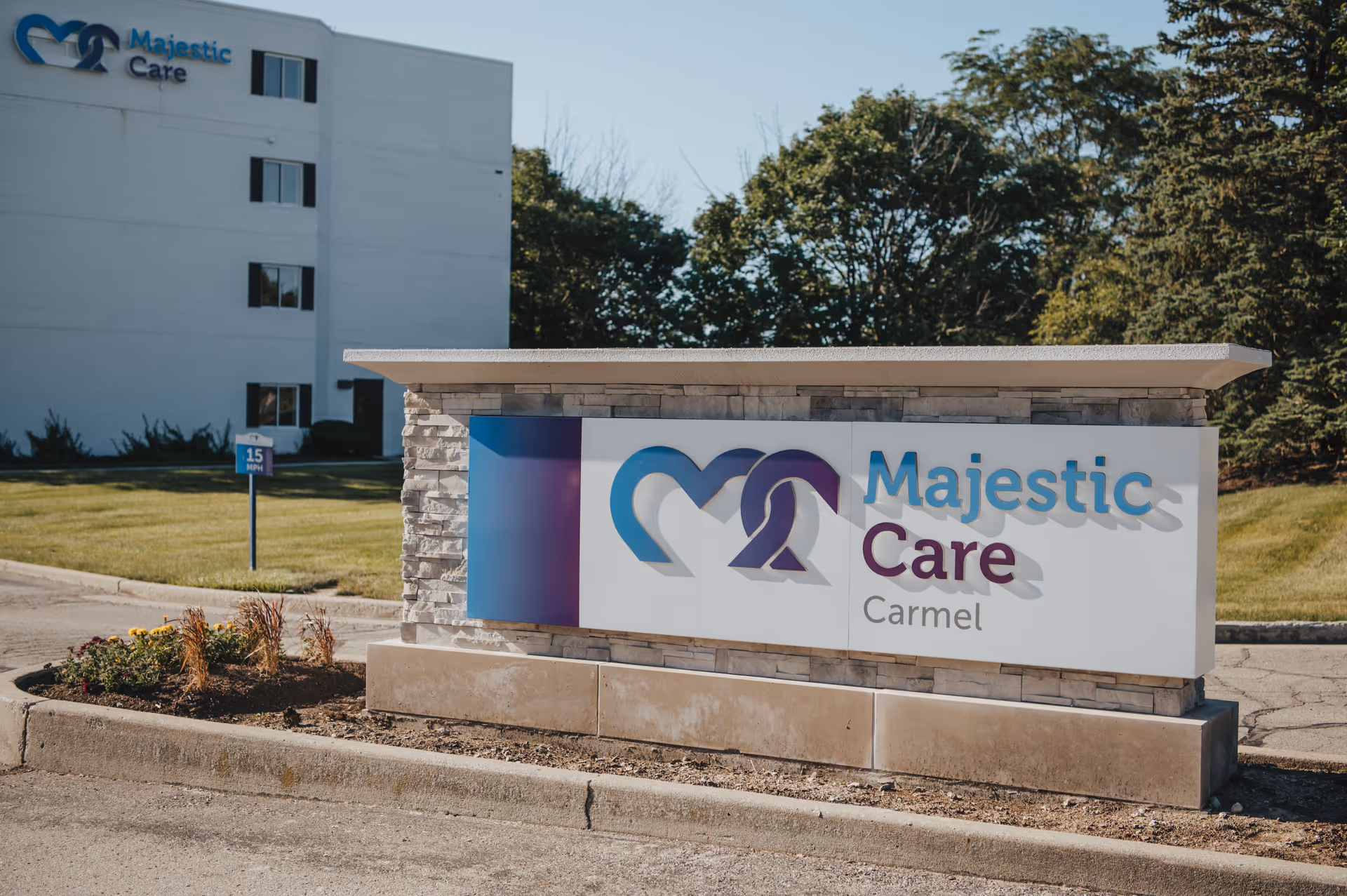 Exterior view of Majestic Care Carmel with a large sign and building in the background.