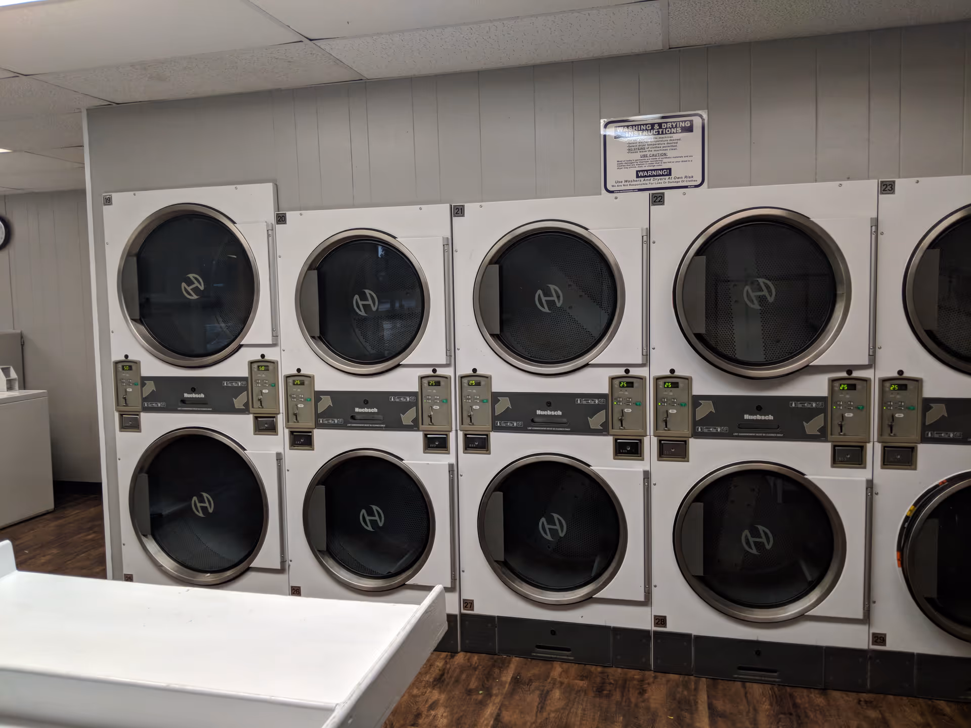 Row of large front-loading washers in a laundry room at a senior care facility.