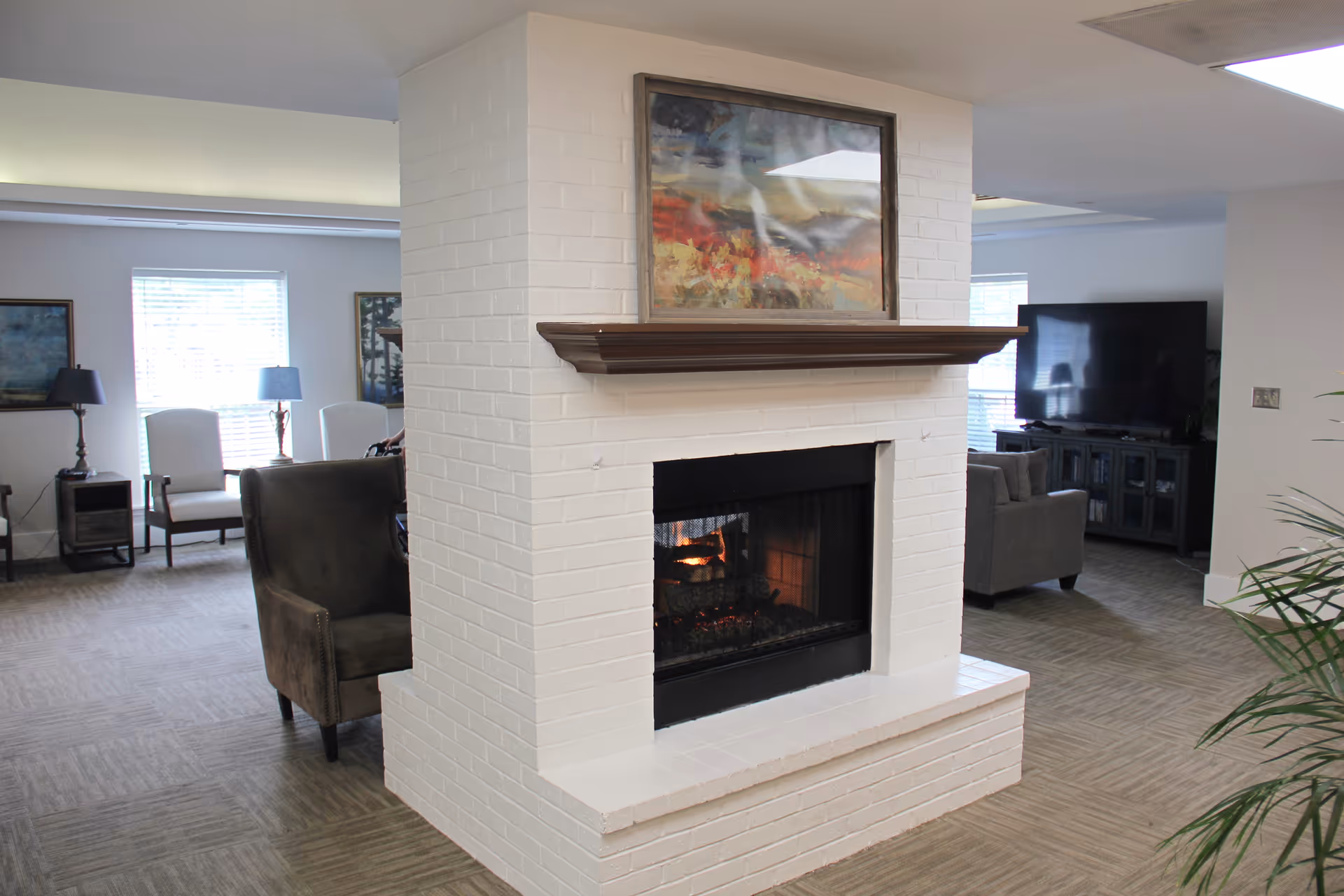 Interior living area featuring a white brick fireplace, mantel, painting, and seating.