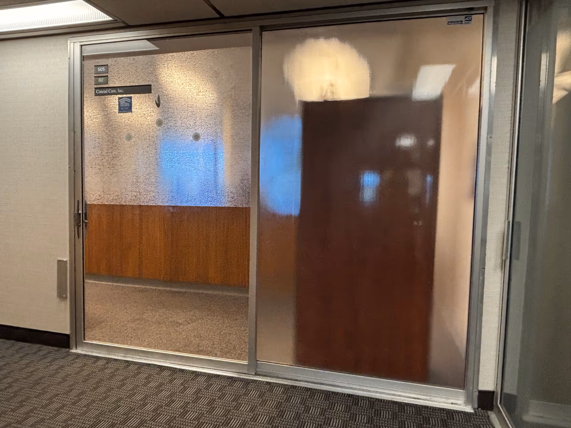 Interior hallway with frosted glass sliding doors and wood paneling along the corridor.