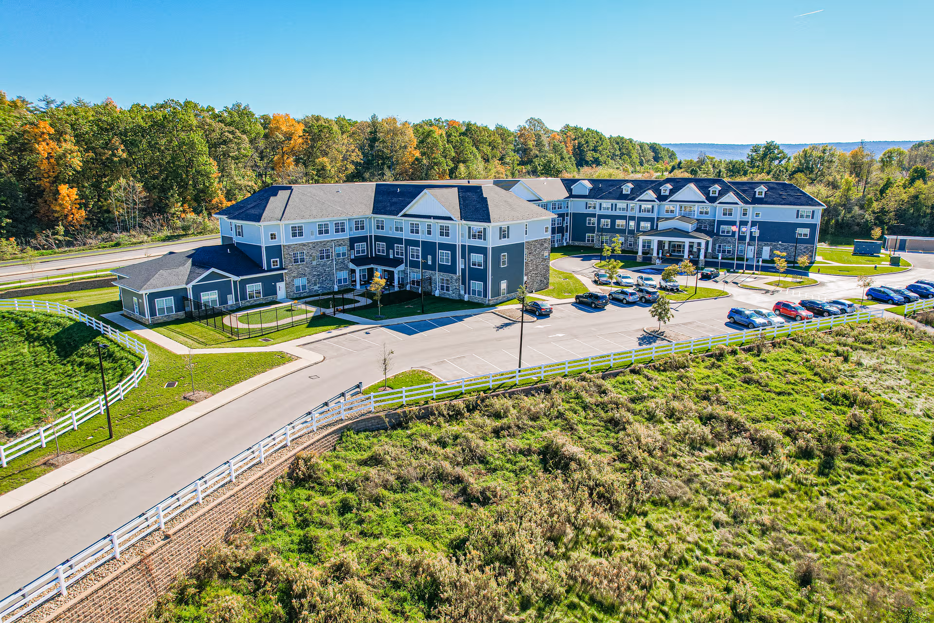 Aerial view of Harmony at State College senior living campus with parking and greenery.