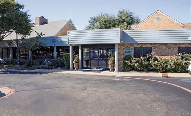 Front entrance of Morada Temple senior living facility with brick facade and potted plants.