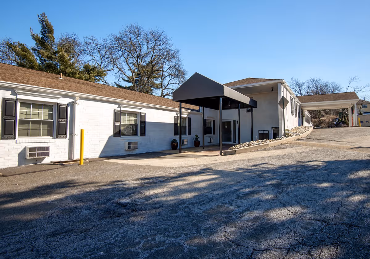 Exterior view of a Genesis Healthcare facility with a covered entrance and parking lot.