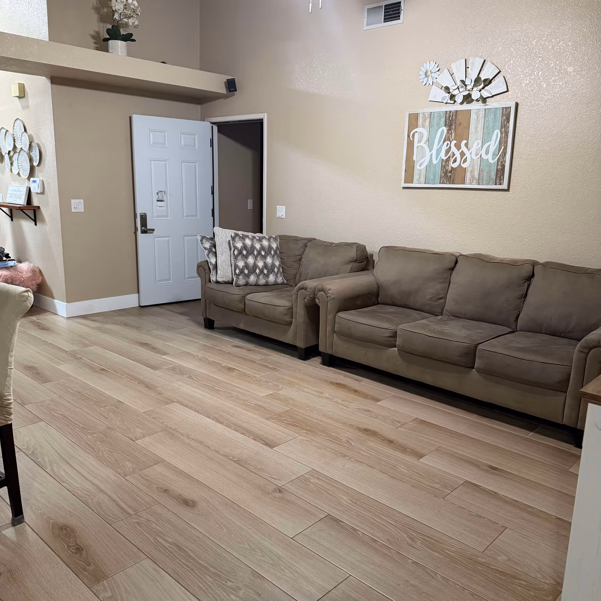 Beige-walled living room featuring a brown sectional sofa and decorative wall art.