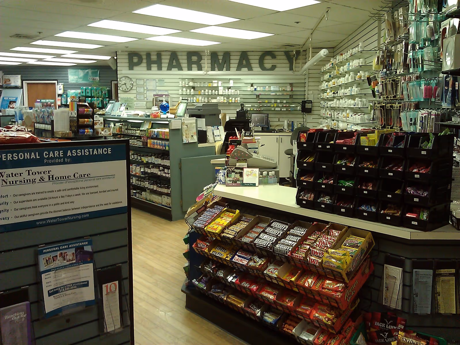 Interior view of a pharmacy with counters, shelves of medications, and a checkout area.