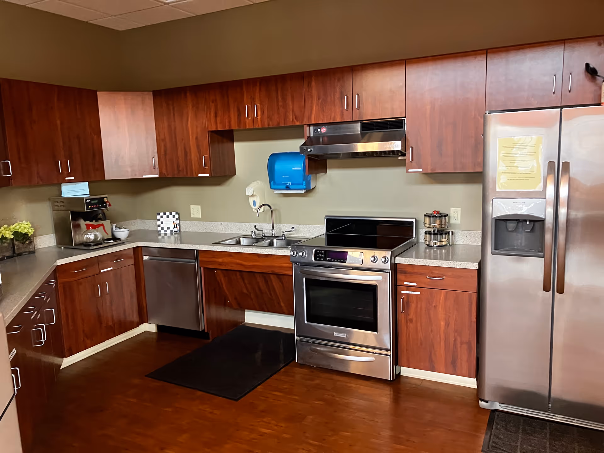 Modern senior-living kitchen with stainless steel appliances and dark wood cabinets.