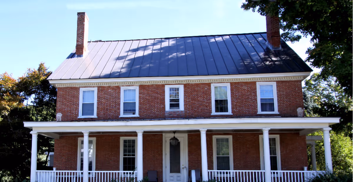 Ascutney House exterior: a two-story brick building with a metal roof and wraparound porch.