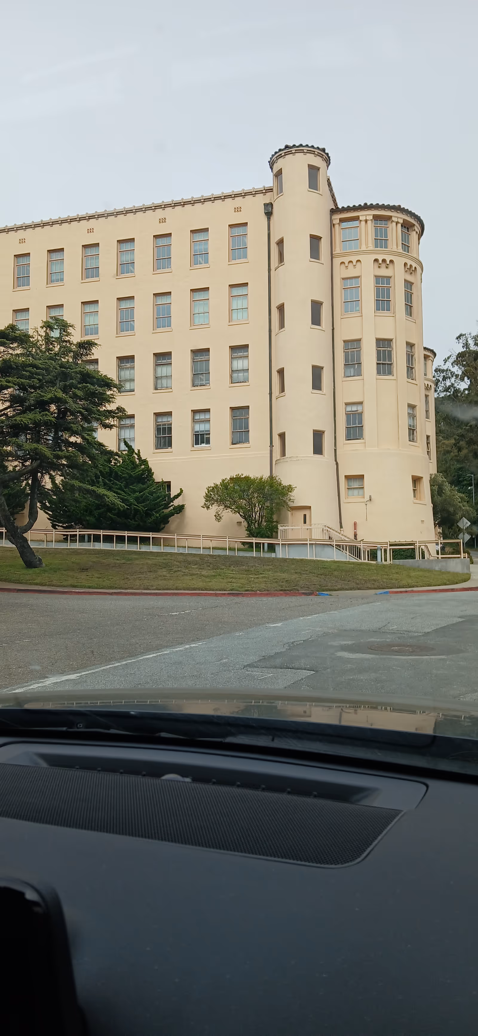 Front view of a beige multi-story hospital building with a rounded turret.